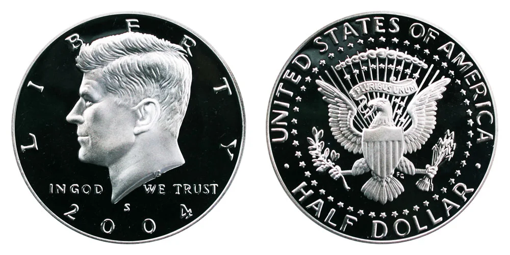2004 Kennedy half dollar grading strip showing four condition tiers: worn/AU, MS-63, MS-65 gem, and MS-67 superb gem examples side by side